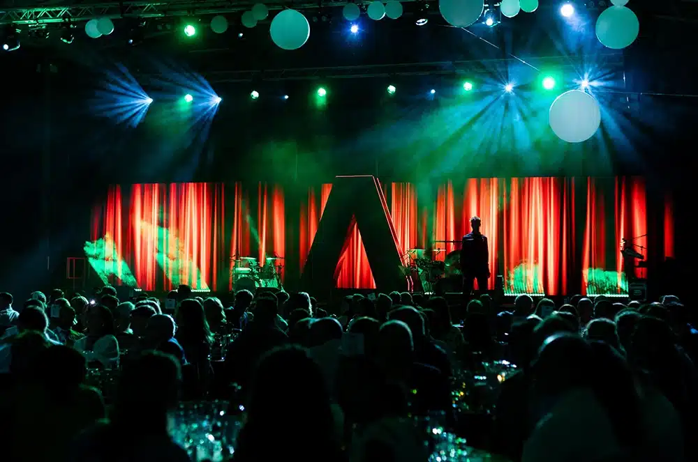 Stage with a bold shape, red and green lighting, and strong event décor creating an immersive and cohesive themed experience